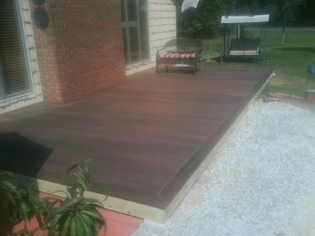 Freshly stained wood deck built against a brick home in Concord