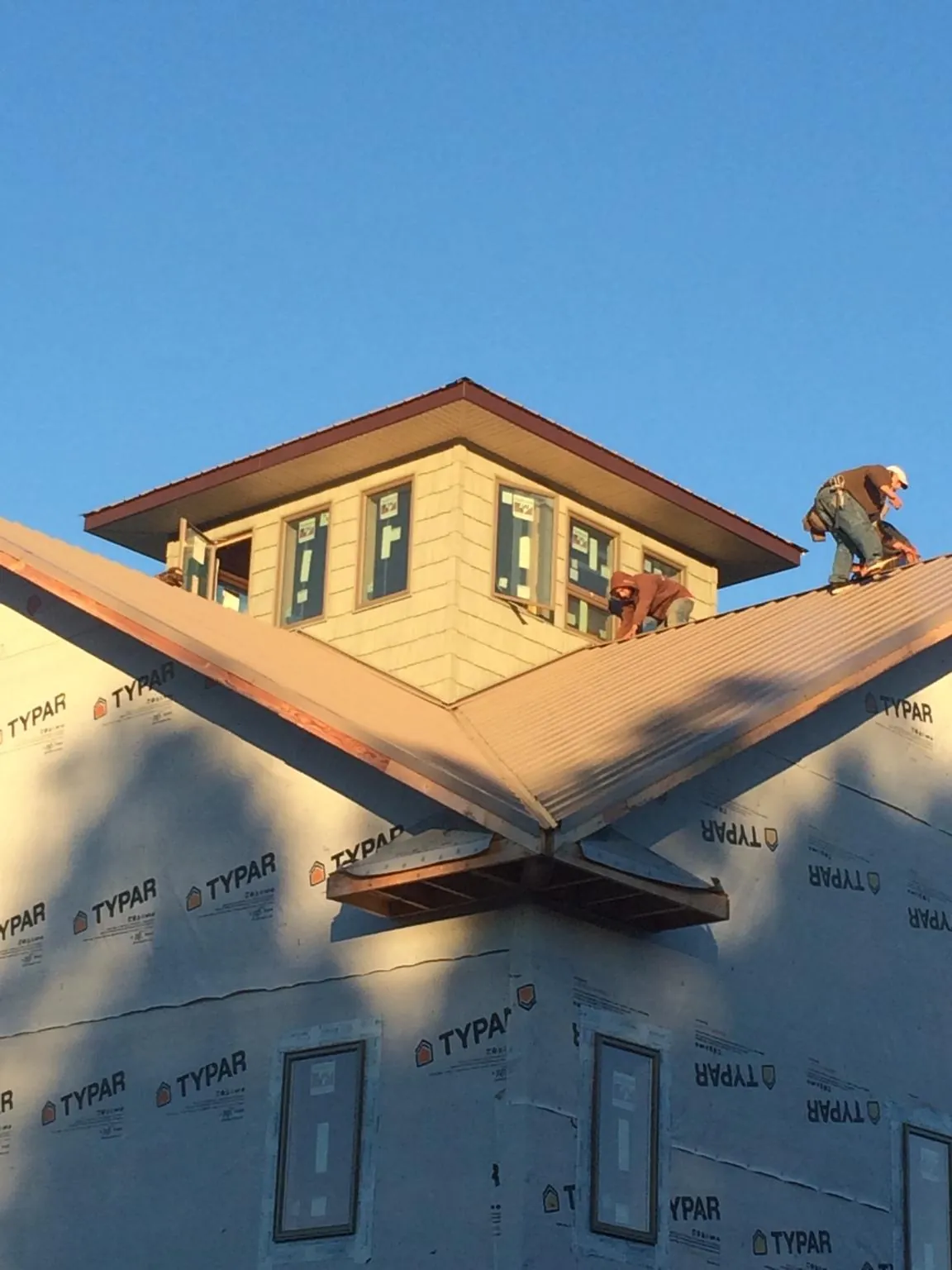 Roofers working around a rooftop cupola on a new metal roof at sunset — Roof Waterproofing in Concord by Roofing Brothers
